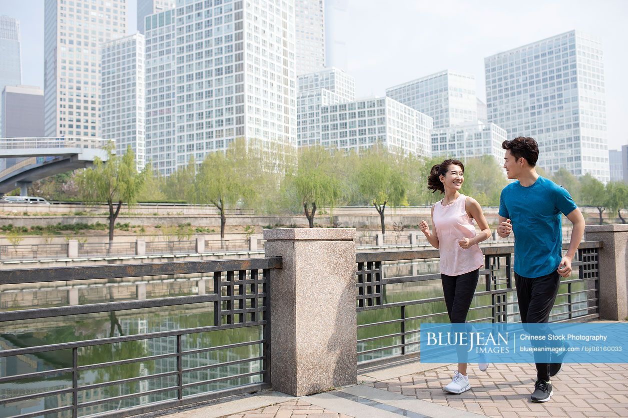 Happy young Chinese couple running in park