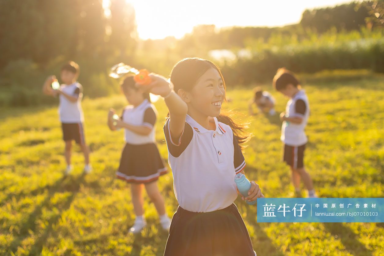 快乐的小学生在草地上吹泡泡