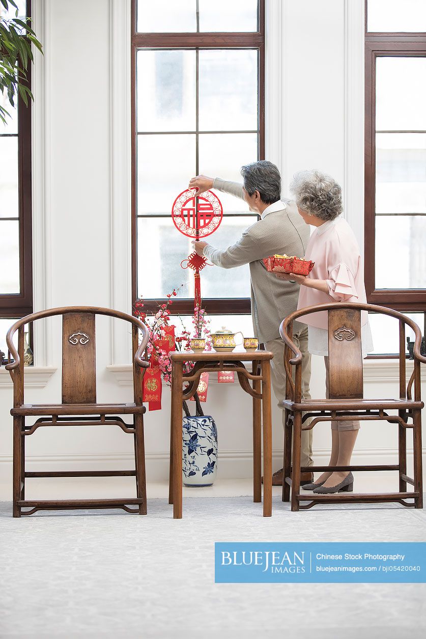 Senior couple decorating their house for Chinese New Year