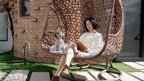 Happy young Chinese woman with pet dog on hanging-chair,4K