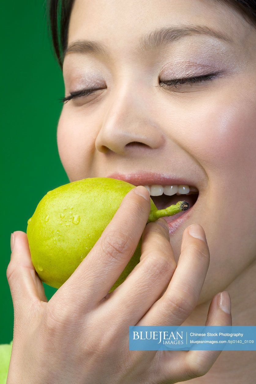 Chinese woman in green eating a lemon