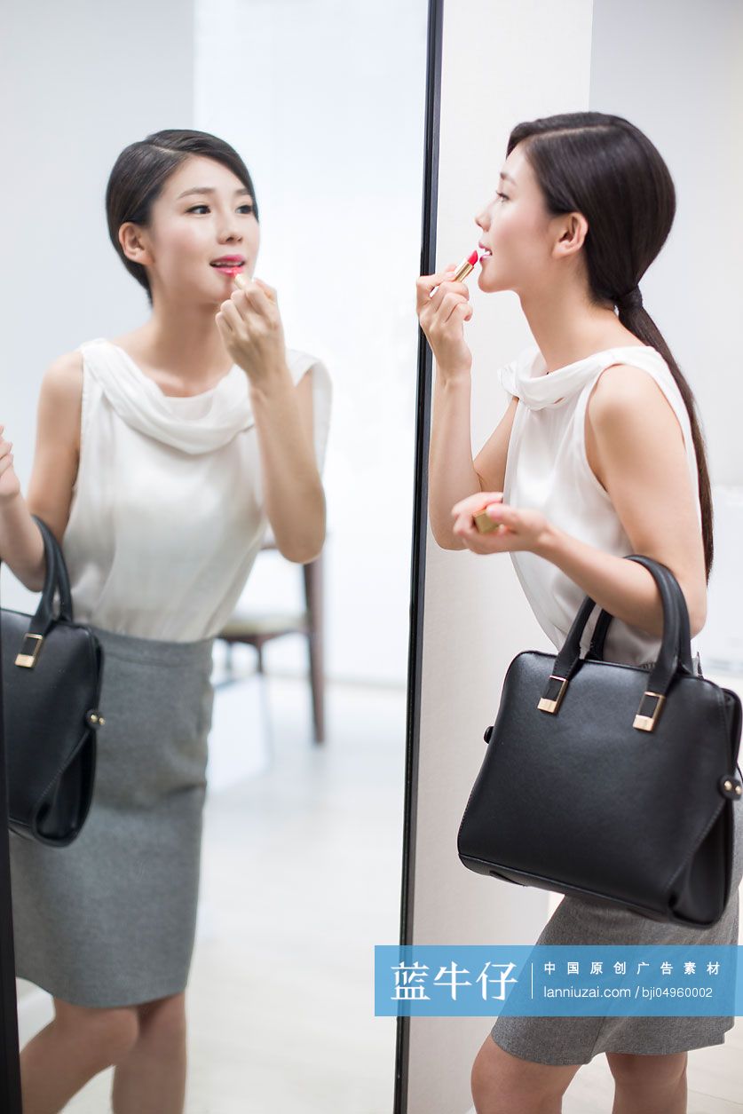 年轻女子在镜子前涂口红
