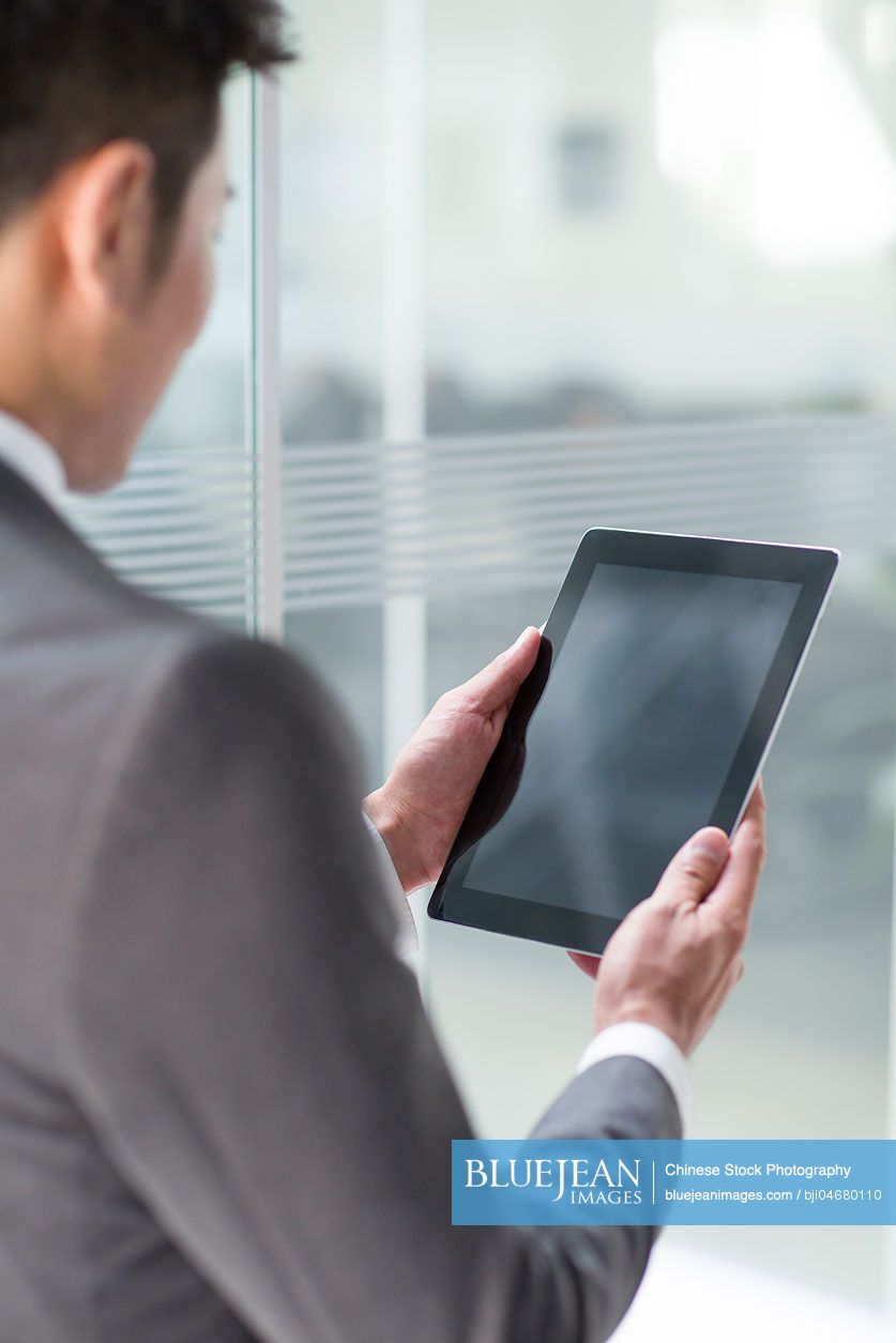 Young Chinese businessman using digital tablet