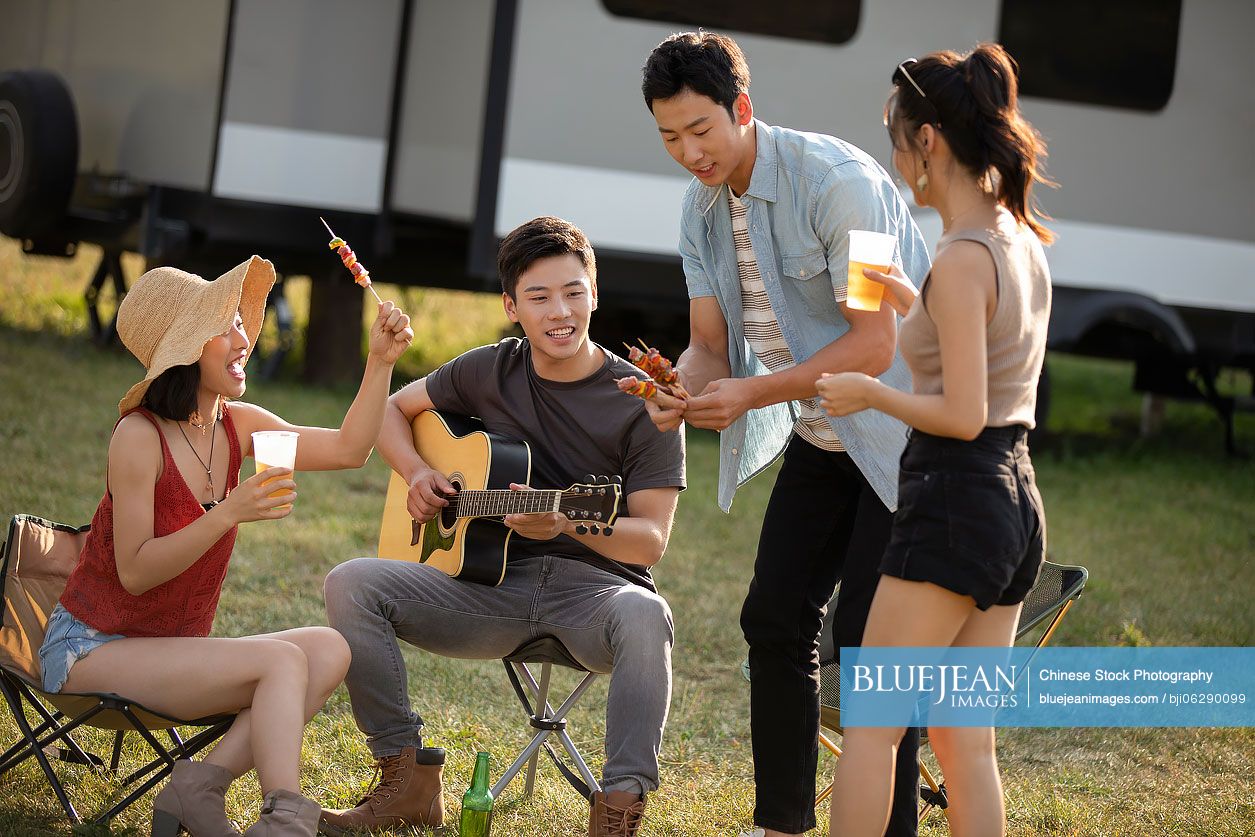 Happy young Chinese friends barbecuing outdoors