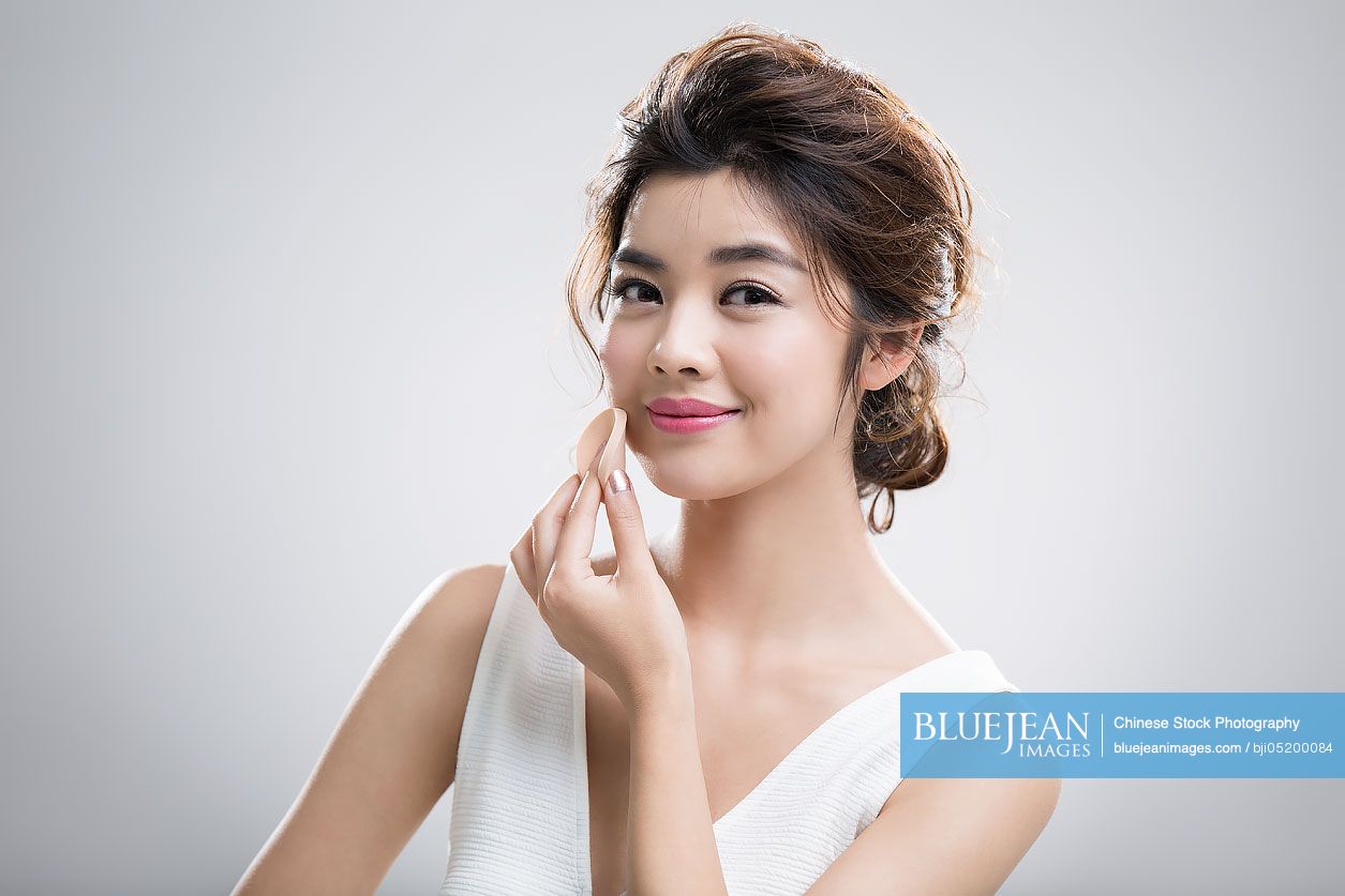 Young Chinese woman applying facial powder