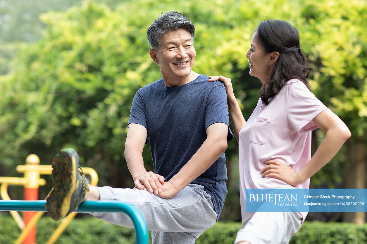 Happy mature Chinese couple exercising in park