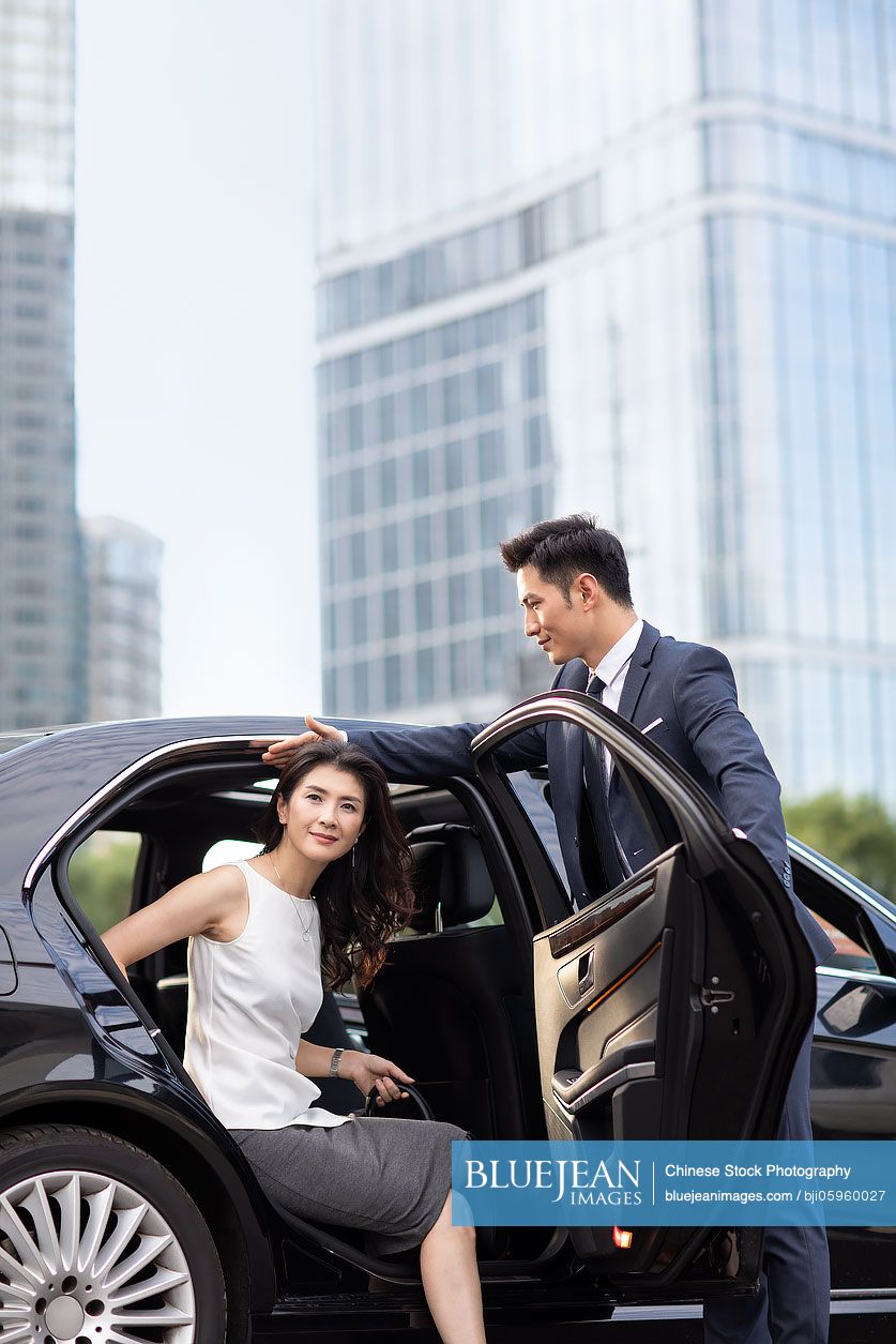 Confident Chinese businesswoman getting out of car