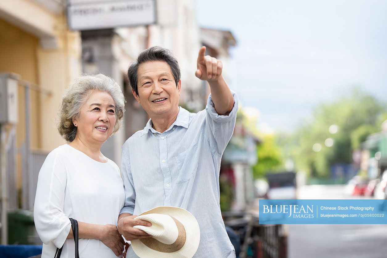 Happy senior Chinese couple standing on street