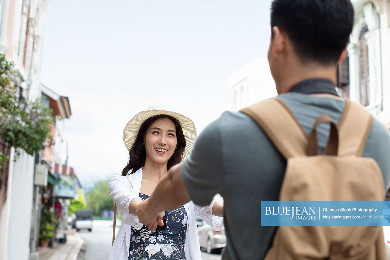 Happy young Chinese couple holding hands on street