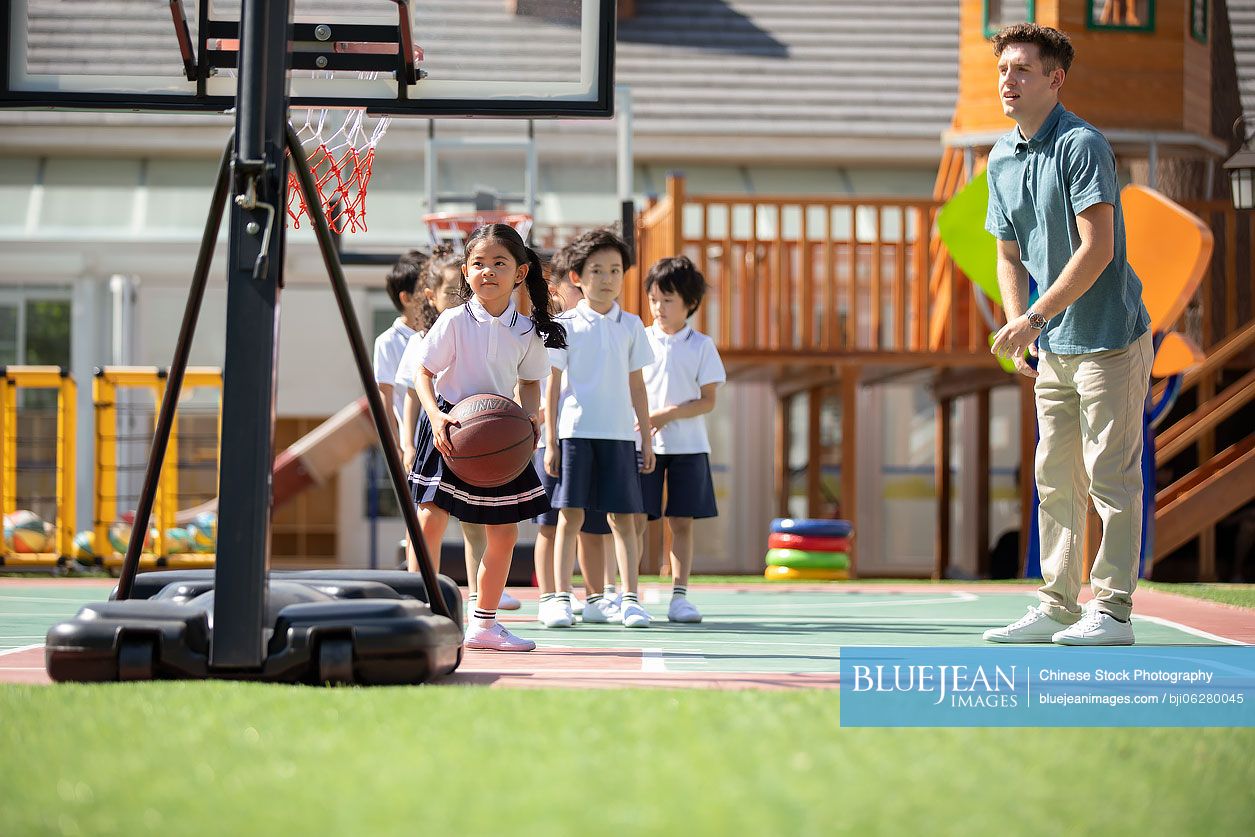 Foreign teacher and children playing basketball in playground