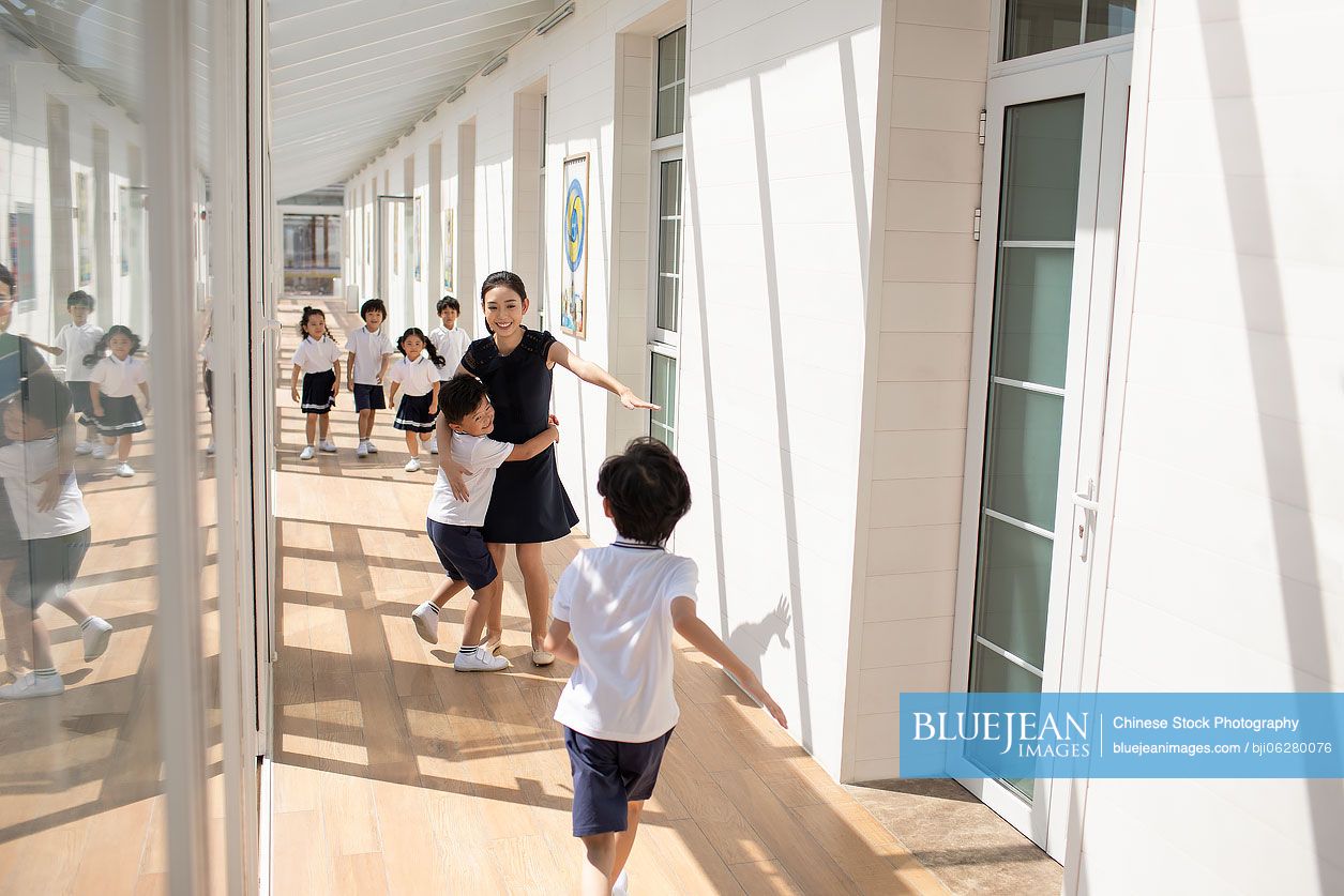 Chinese teacher and children in school hallway