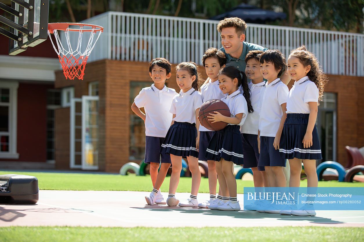 Foreign teacher and children playing basketball in playground