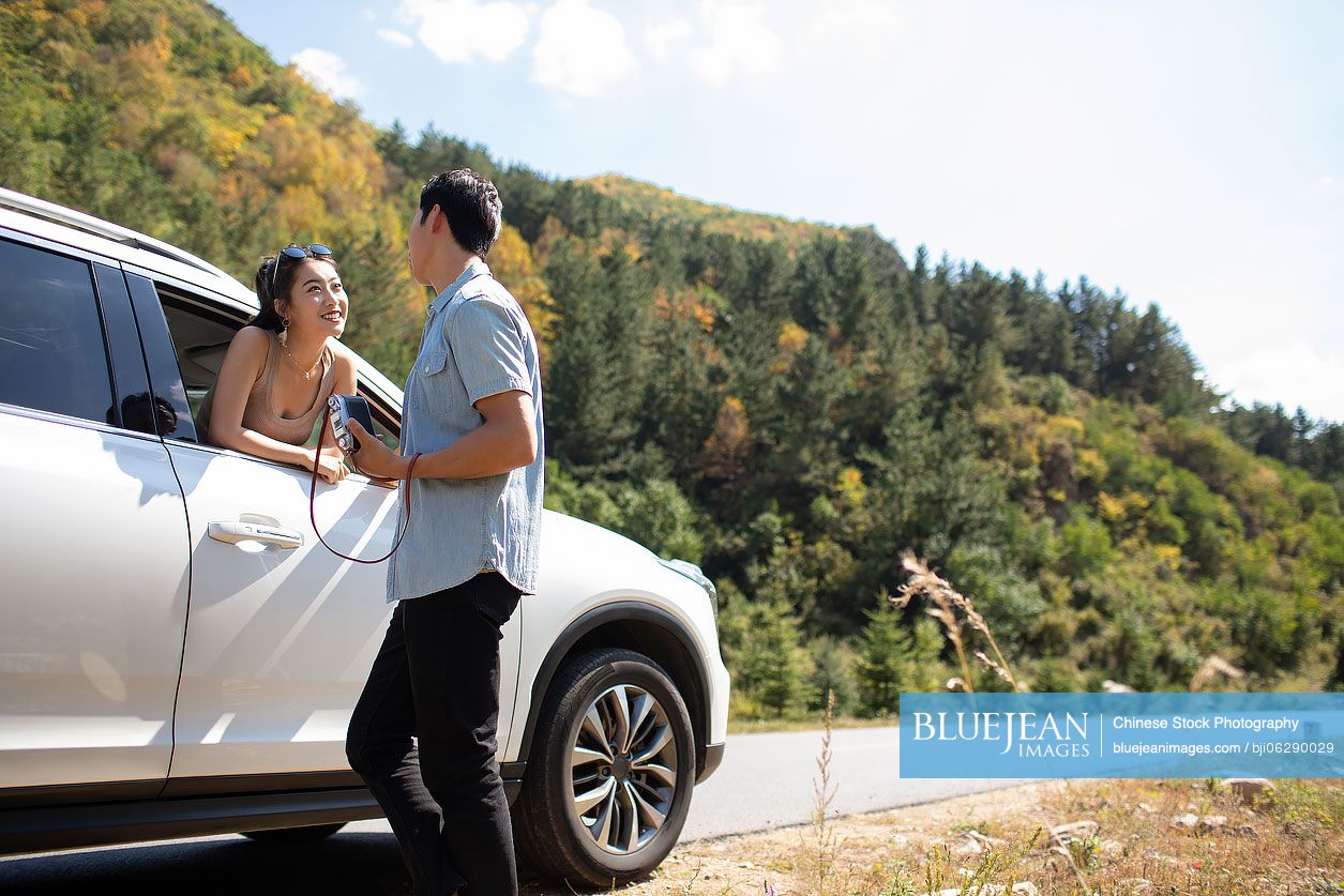 Happy young Chinese couple enjoying road trip