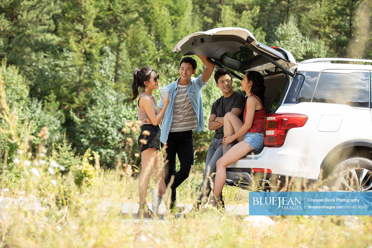 Happy young Chinese friends enjoying road trip