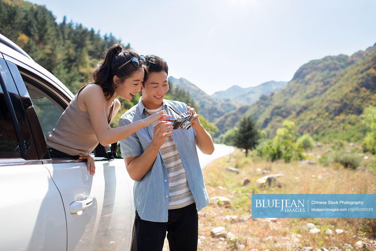 Happy young Chinese couple enjoying road trip