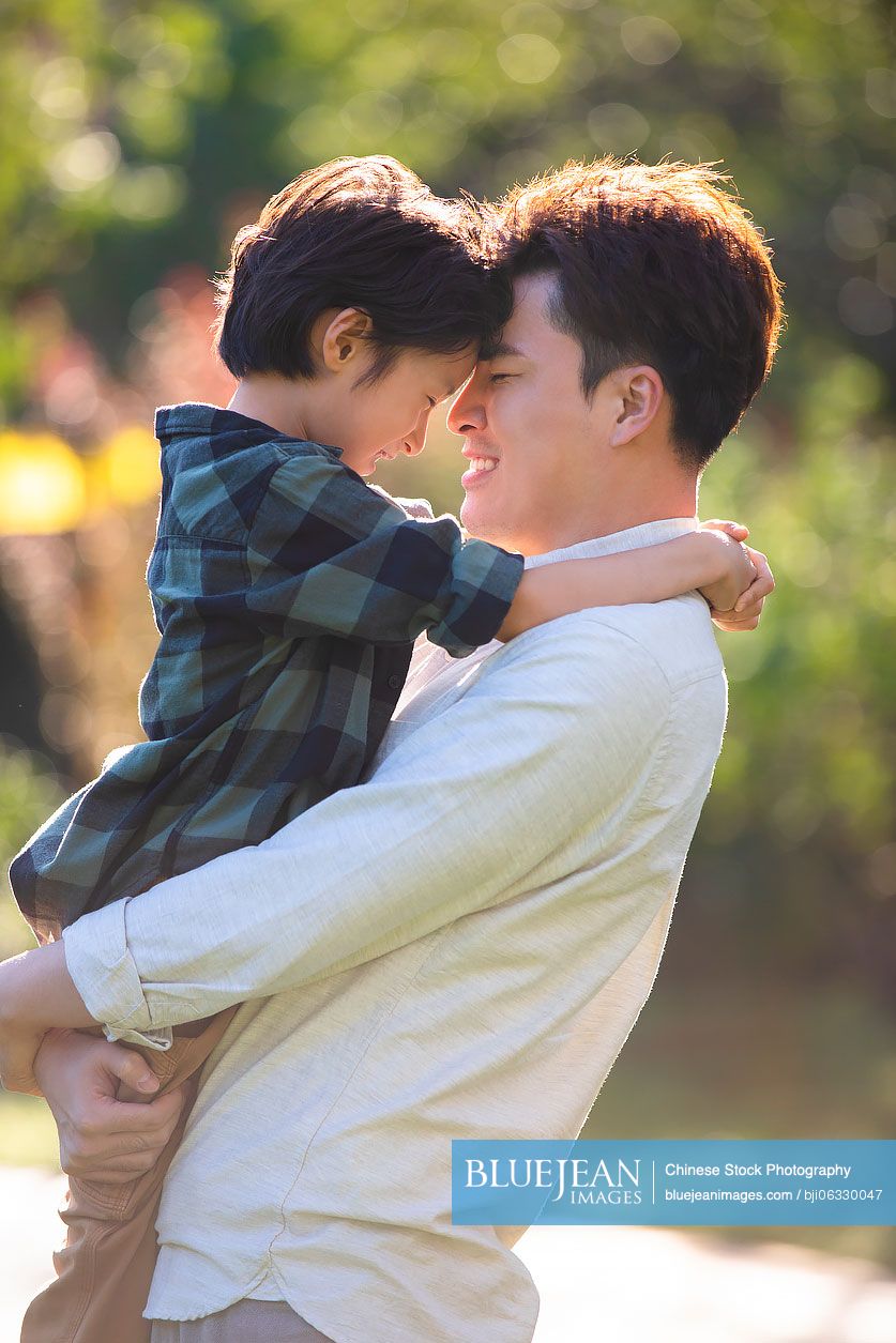 Happy Chinese father and son relaxing in park