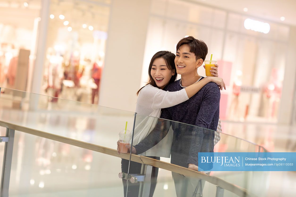 Happy young Chinese couple dating in shopping mall