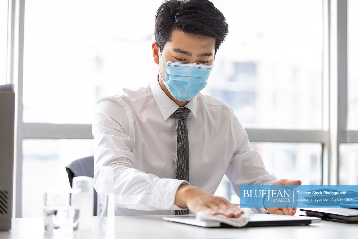 Young Chinese businessman using disinfectant in office