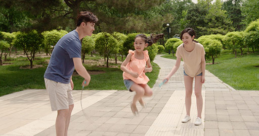 Happy young Chinese family jumping rope in park,4K