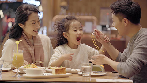 快乐的年轻家庭在餐厅就餐