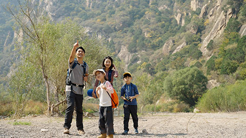 Happy young Chinese family hiking outdoors