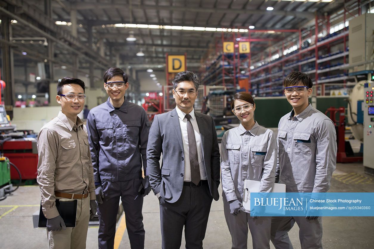 Confident Chinese businessman and engineering team in the factory