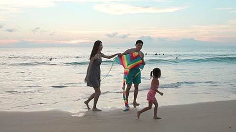 Happy young Chinese family flying a kite on beach,4K