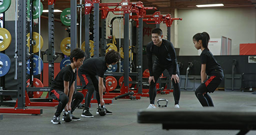 Active Chinese children having exercise class with their coach in gym,4K