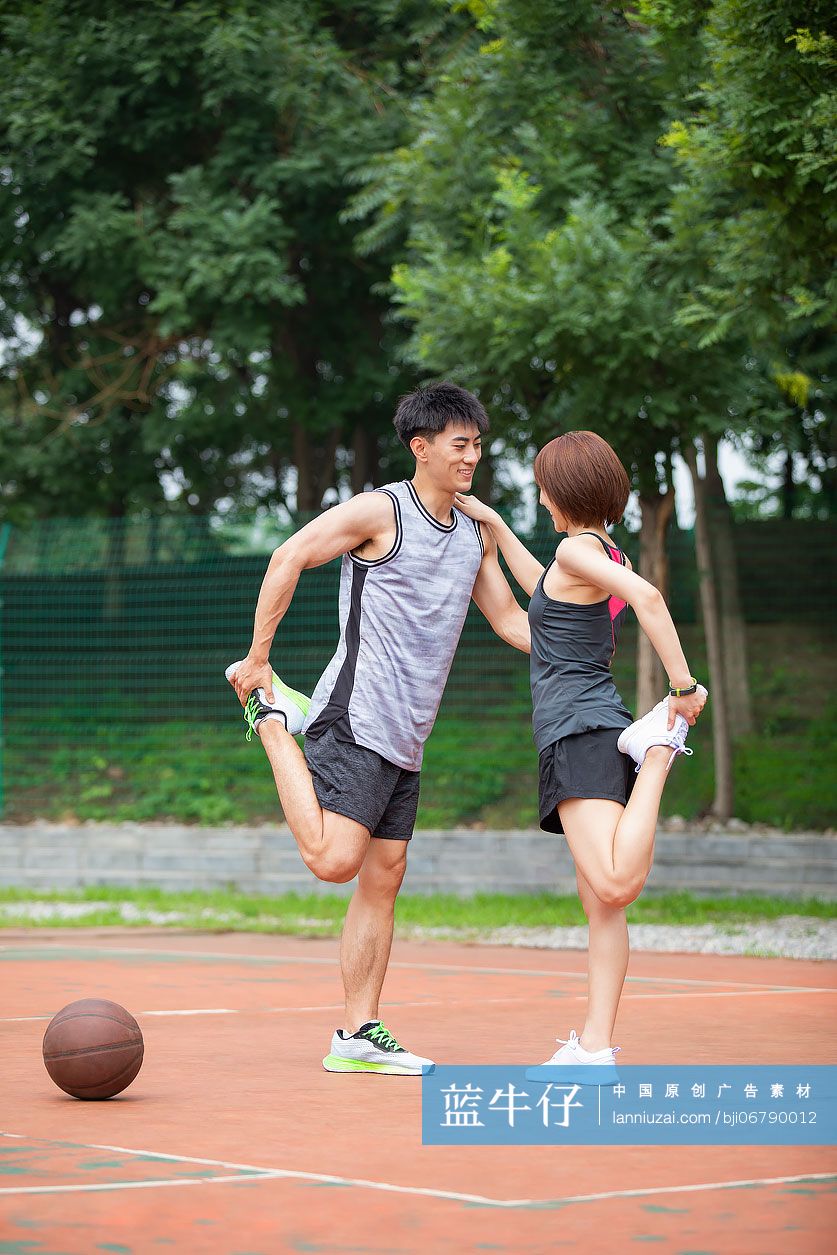 开心的年轻情侣在篮球场打篮球