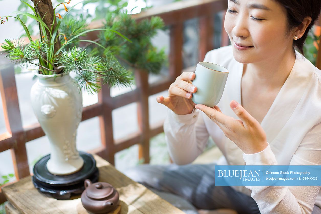 Mid adult Chinese woman drinking tea in tea room