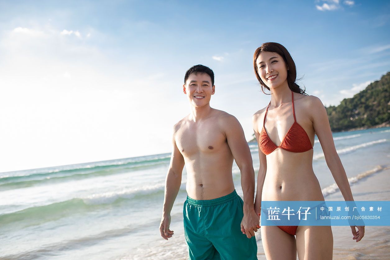 快乐的年轻情侣在沙滩散步