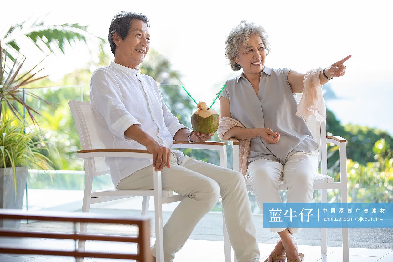 快乐的老年夫妇在阳台喝椰汁