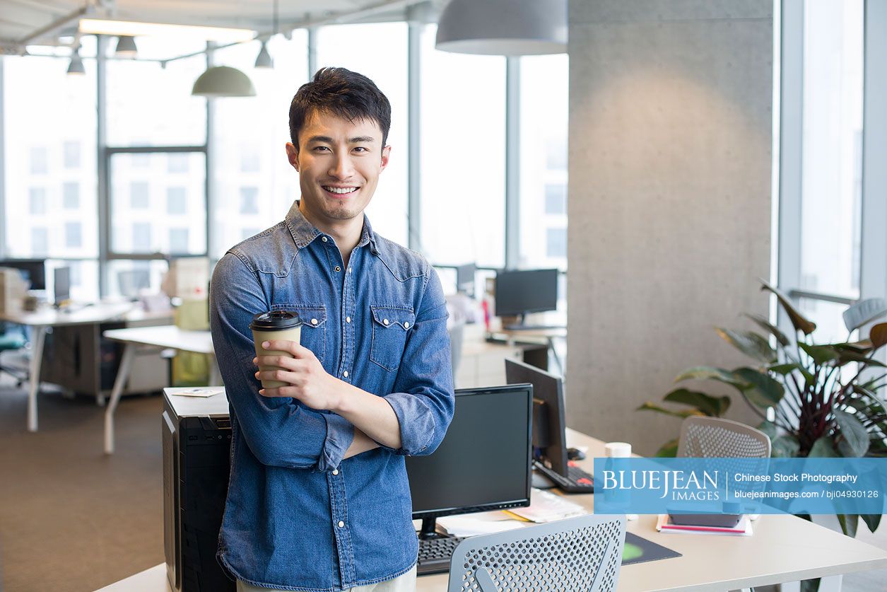 Portrait of confident young Chinese man in office