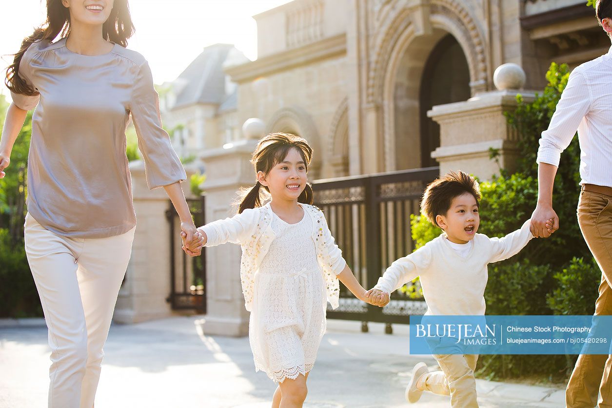 Happy young Chinese family holding hands running