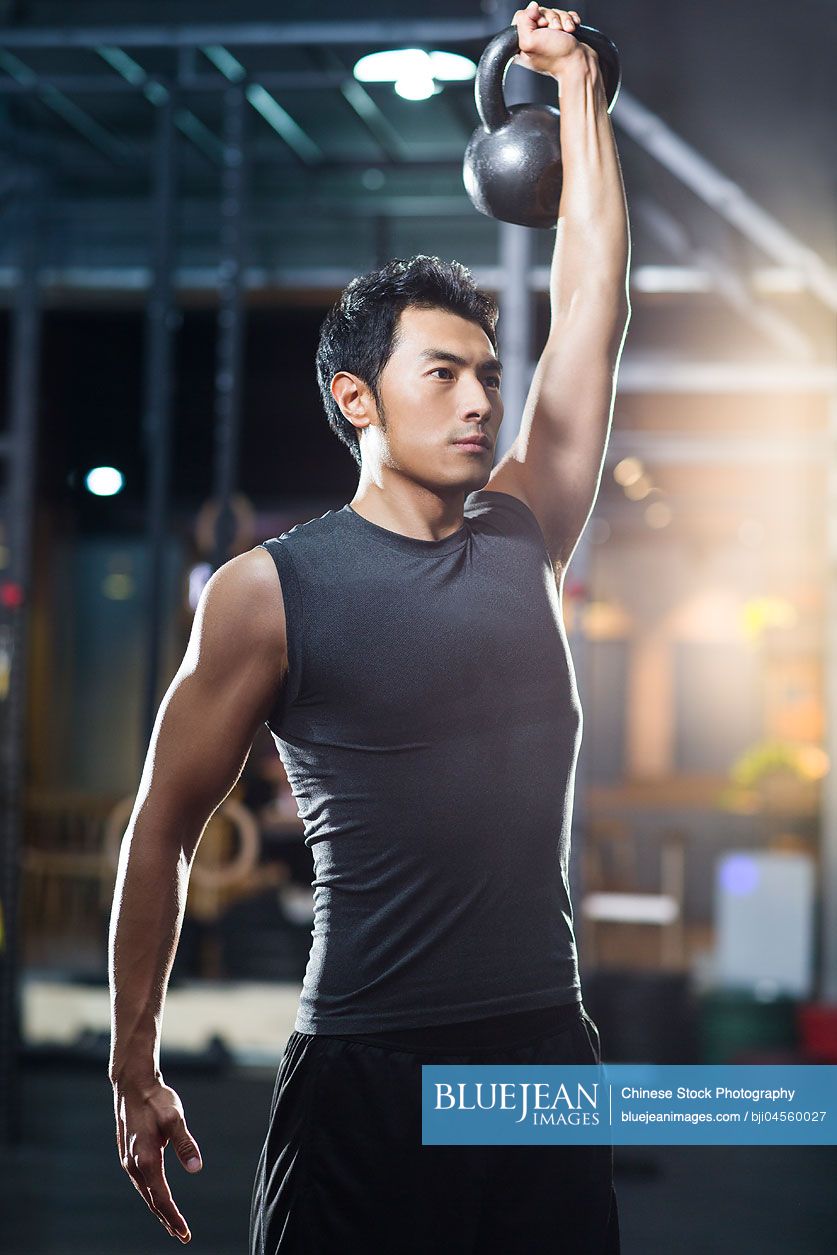 Young Chinese man training with kettlebell in crossfit gym