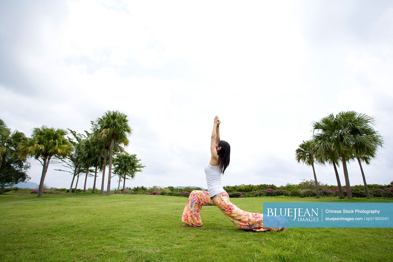 Young Chinese woman doing yoga in grass