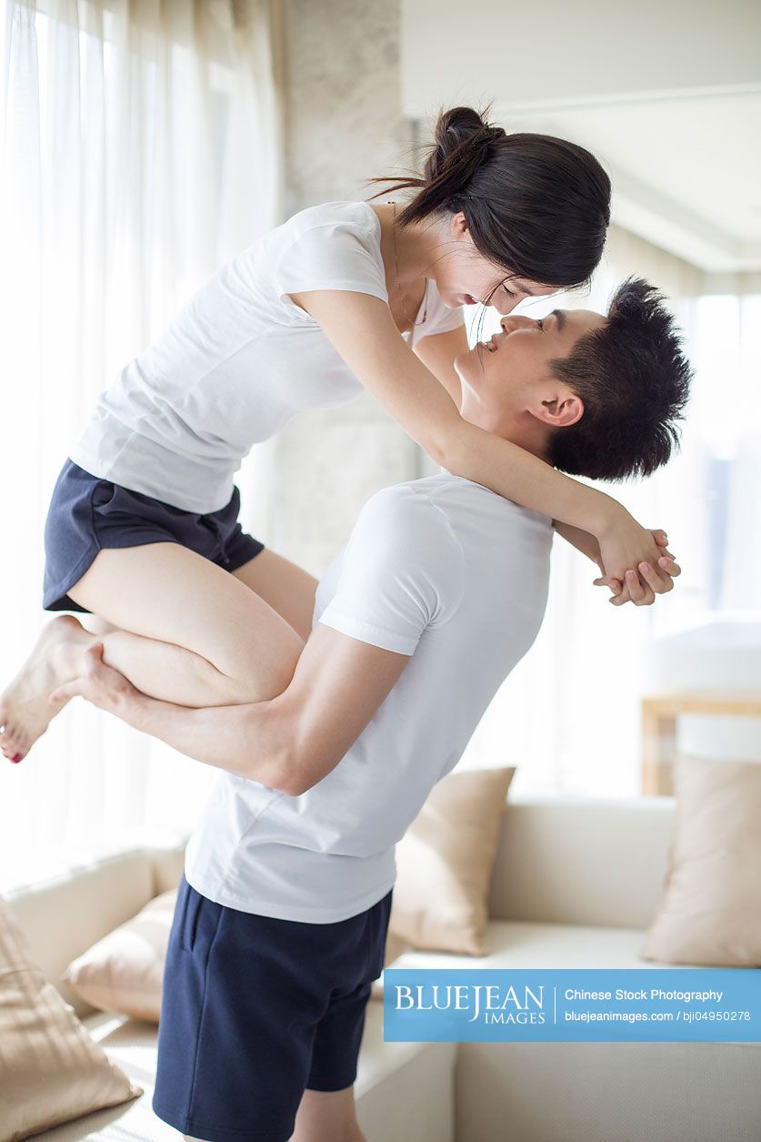 Happy young Chinese couple relaxing at home