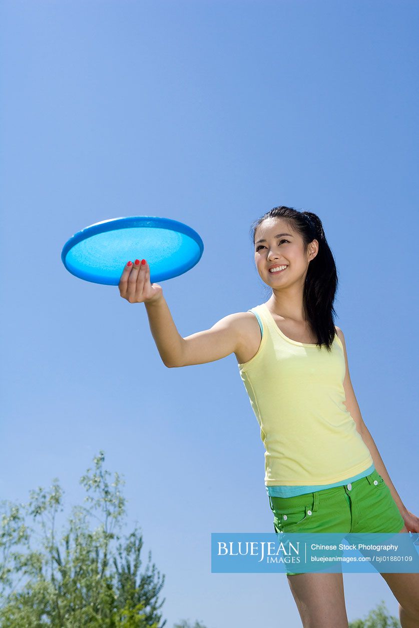 Young Chinese woman throwing a Frisbee