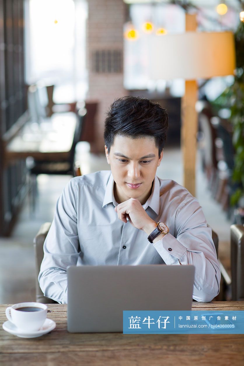 年轻男子在咖啡馆使用笔记本电脑