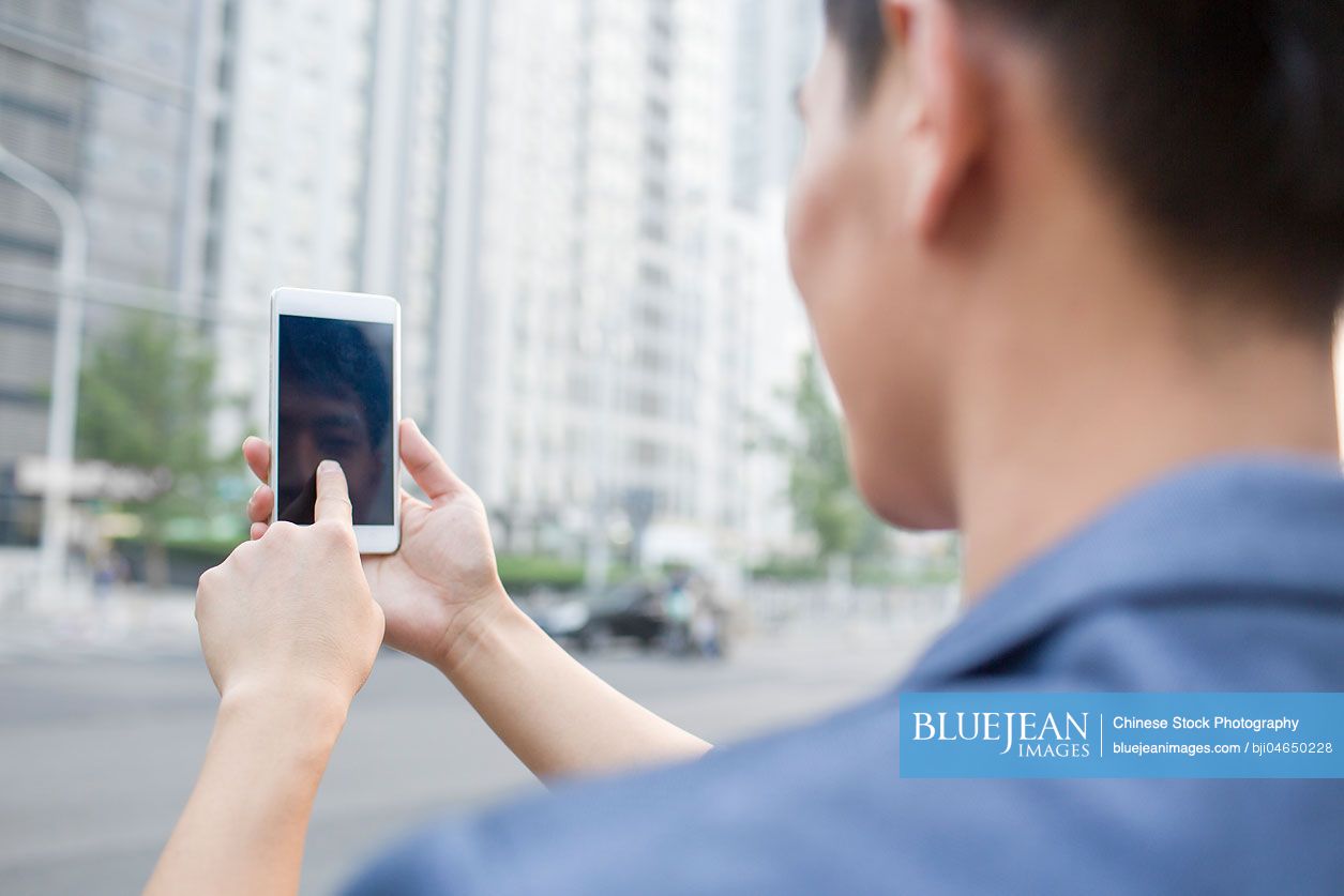 Young Chinese man using smart phone