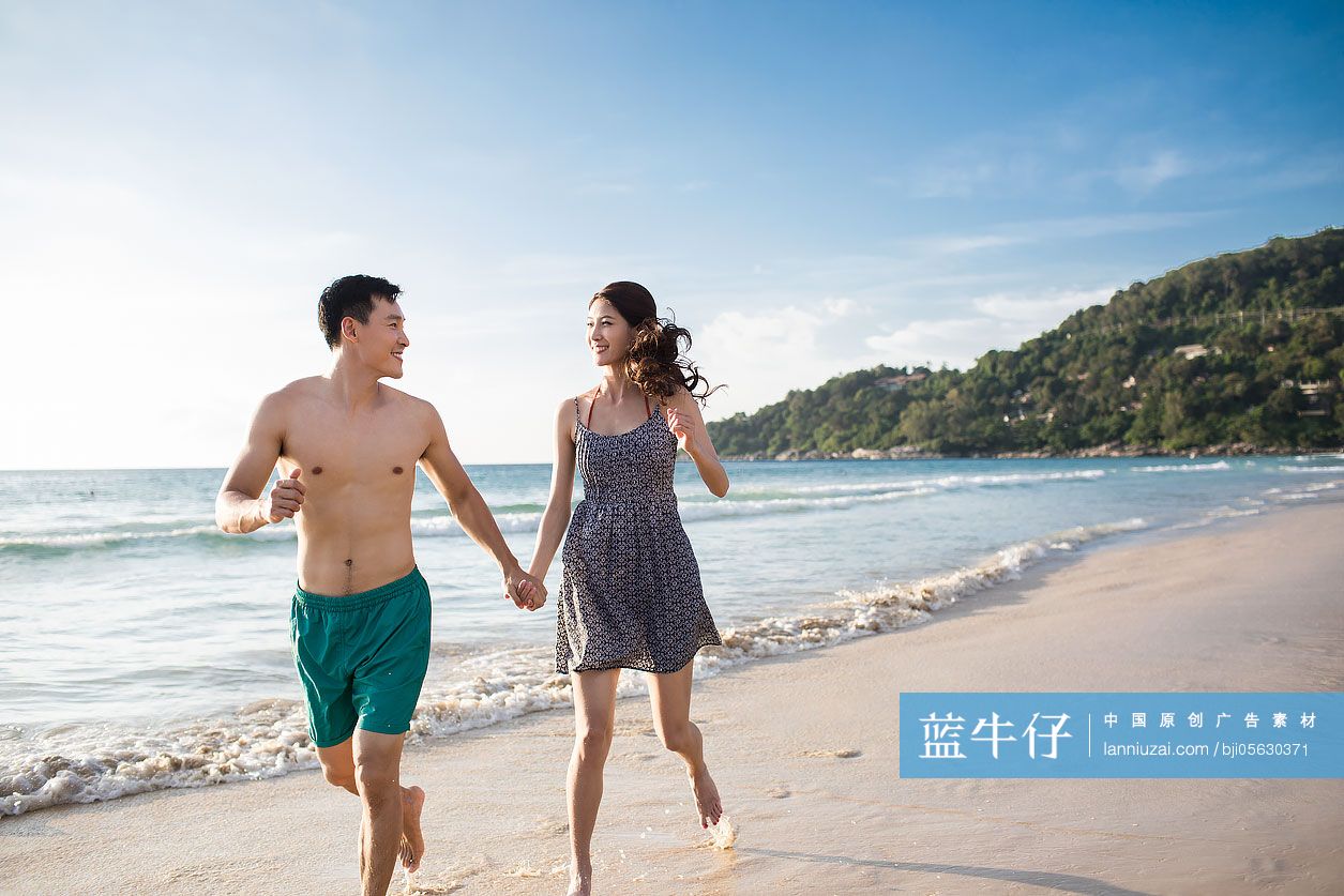 快乐的年轻情侣在沙滩奔跑
