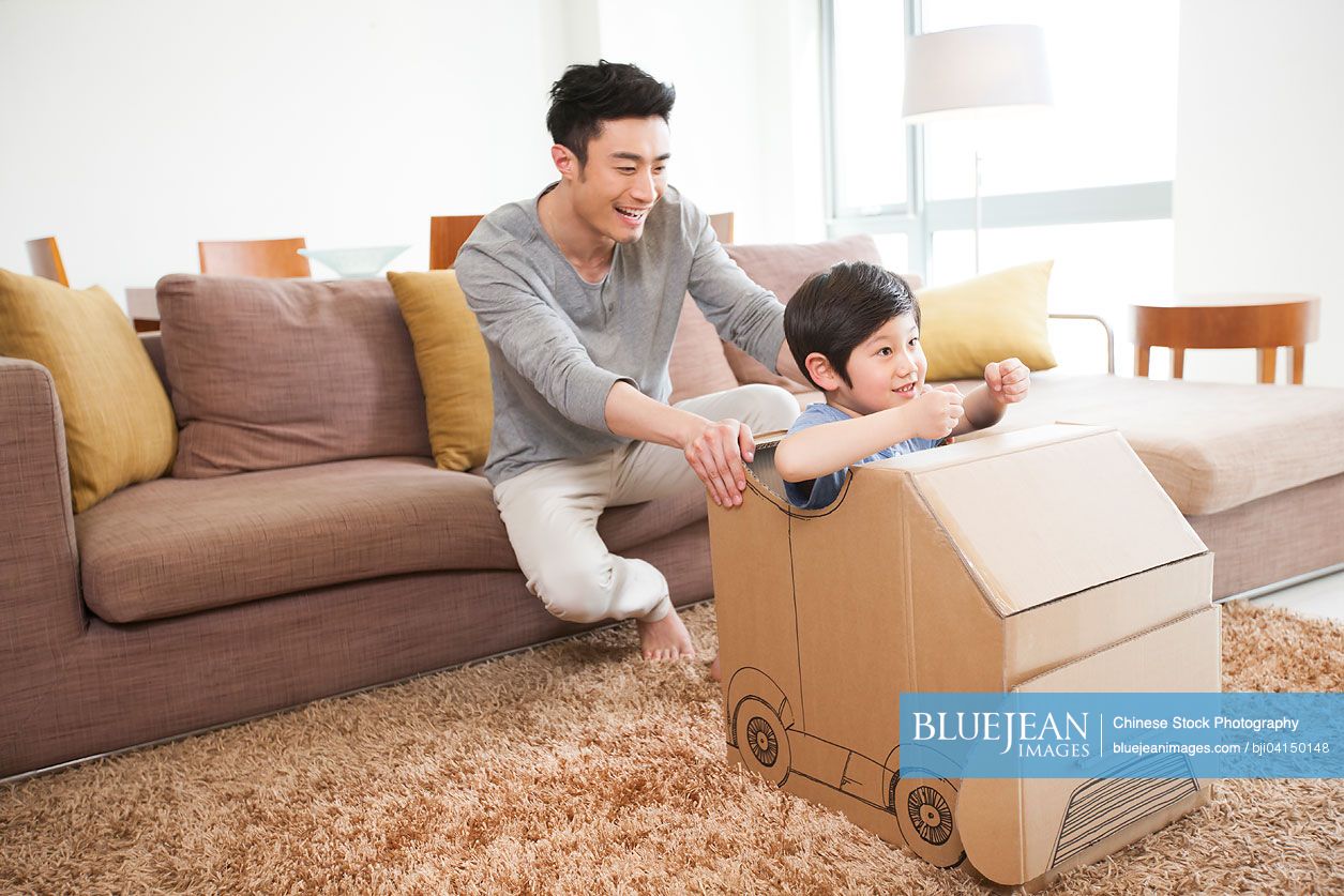 Chinese father and son playing carton car in living room