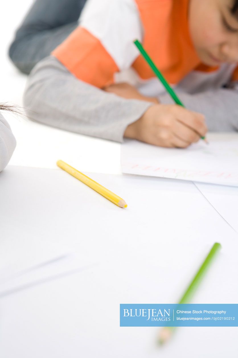 Color pencils in foreground and Chinese boy coloring in the background