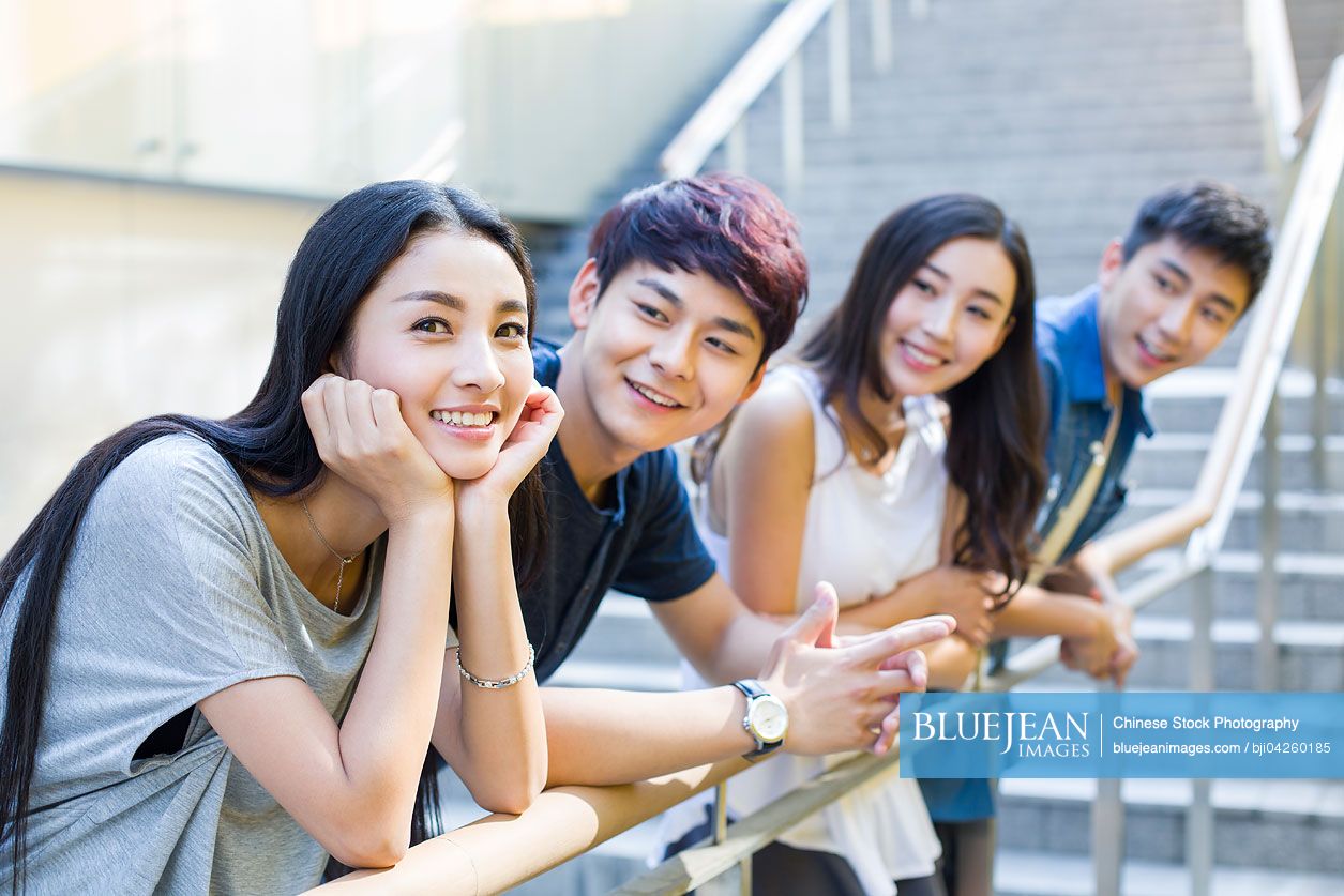 Happy young Chinese woman standing together with her friends