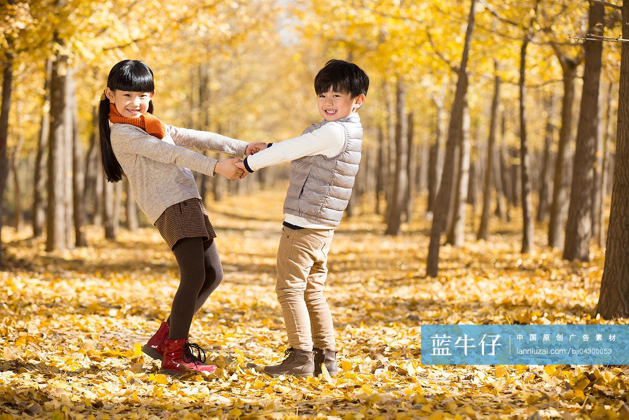 两个小孩在秋日的树林里嬉戏