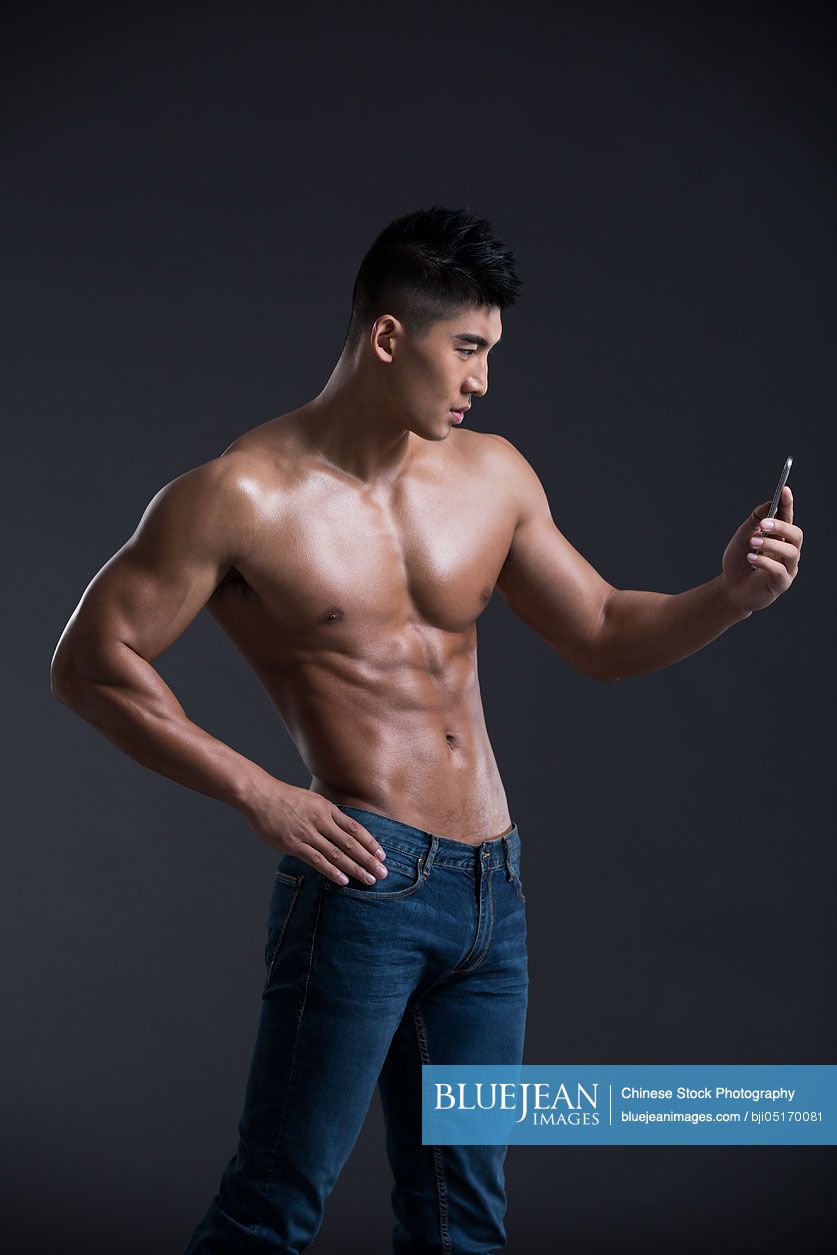 Young Chinese muscular man using smart phone