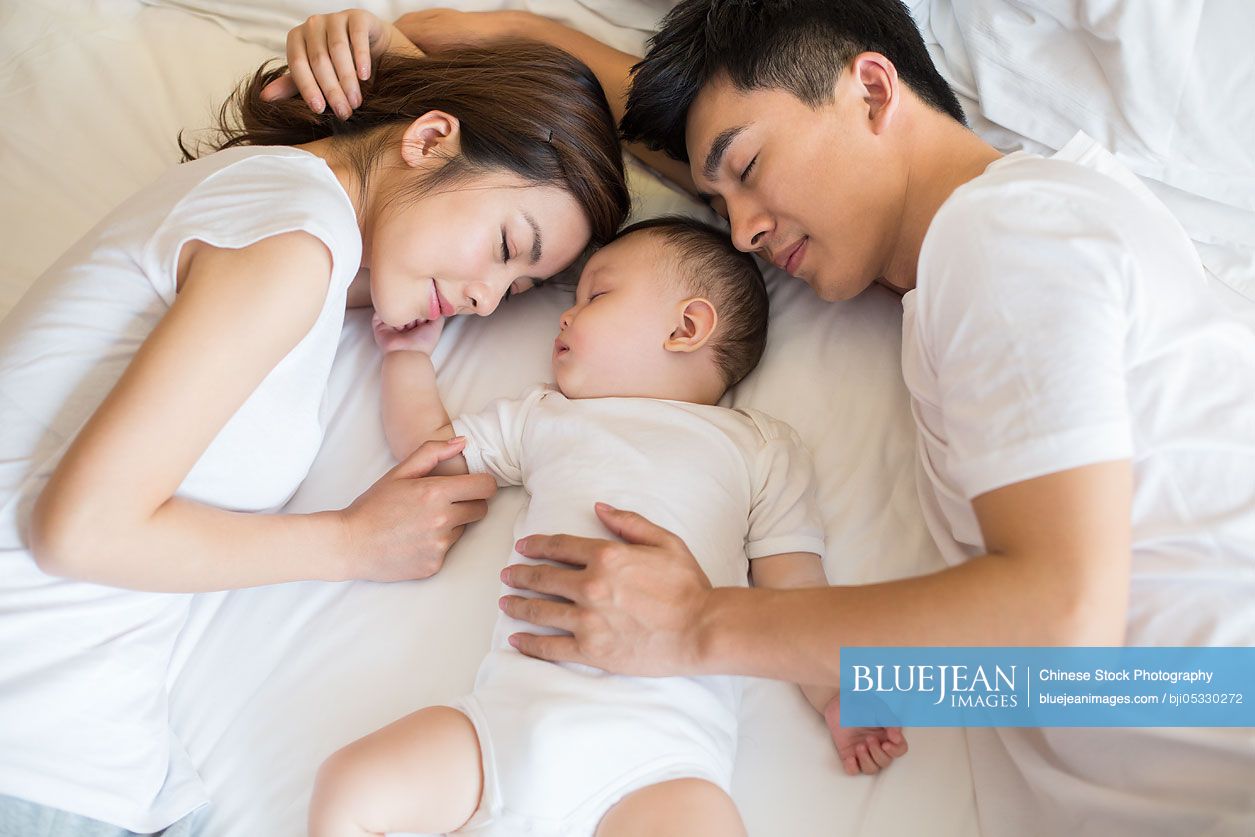 Young Chinese family sleeping in bed