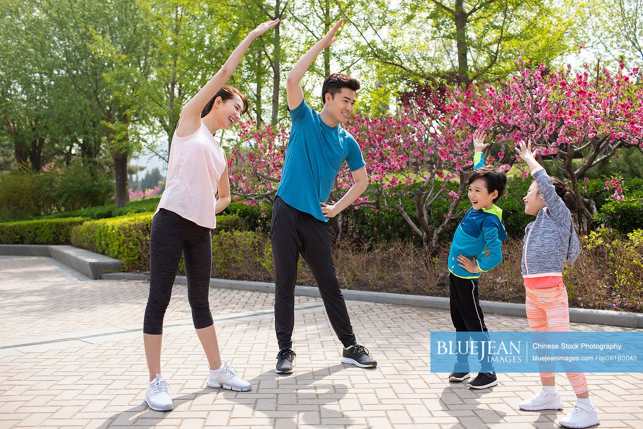 Happy young Chinese family exercising in park