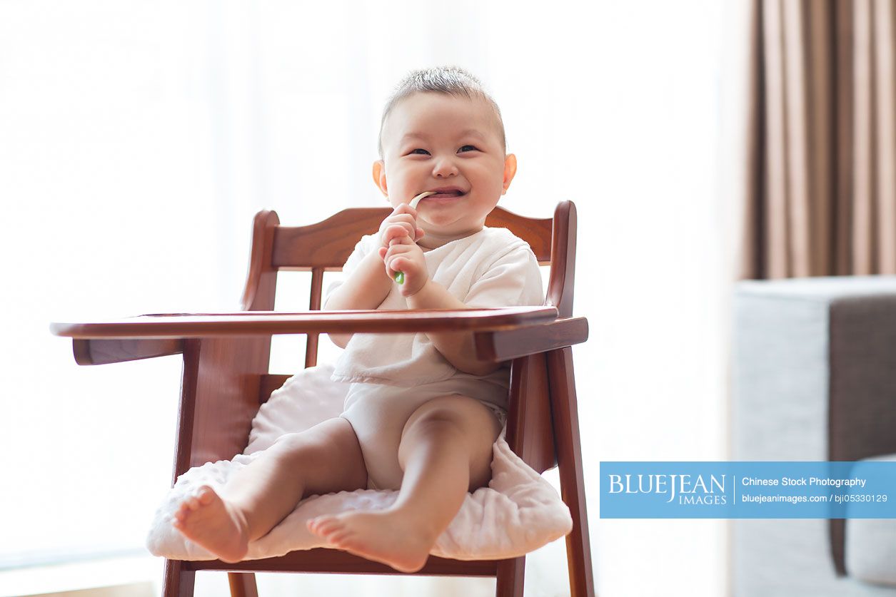 Cute Chinese baby boy sitting in high chair