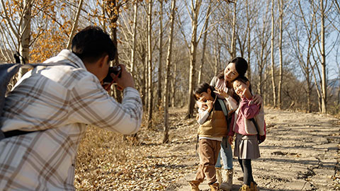 Happy young Chinese family taking photos outdoors